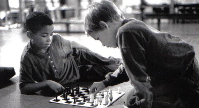 IT funders header image Two young boys concentrate while playing a game of chess, and black and white photo from the 1980's
